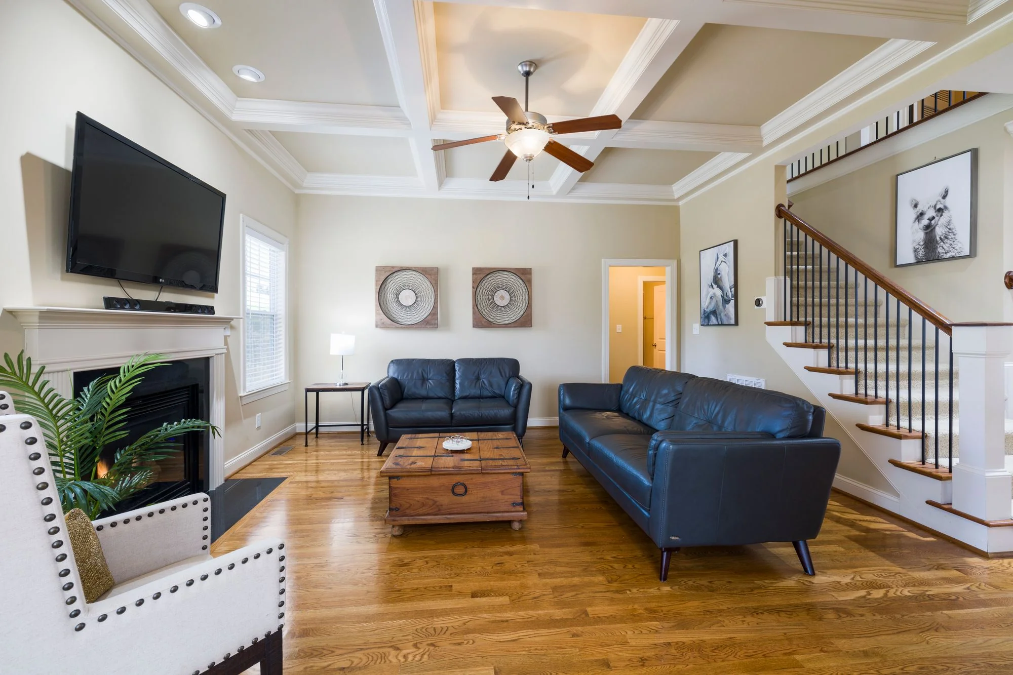 Living room with coffered ceiling, fireplace, and leather sofas
